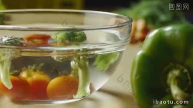 <strong>西红柿</strong>和西兰花与辣椒和其他蔬菜一起放在厨房桌子上的一碗水里洗